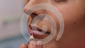 Make up artist applying lipstick. close-up of the lips of a young woman, professional makeup artist with a brush applies