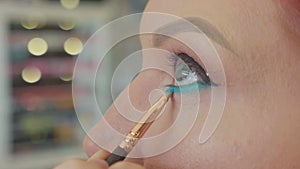 Make-up artist applying makeup to model`s eye. Close up view.