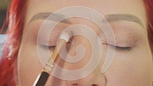 Make-up artist applying makeup to model`s eye. Close up view.