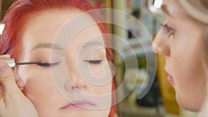 Make-up artist applying makeup to model`s eye. Close up view.