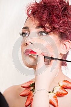 Make-up artist applying the red lipstick of the female model`s w