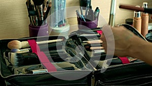 Make-up artist arranging cosmetic brushes in a big professional set