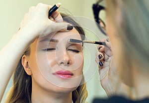 Make-up artist combing eyebrow.