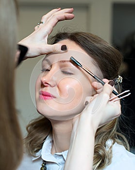 Make-up artist combing eyebrow.