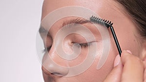 The make-up artist combs the eyebrows and makes the styling of the eyebrows with a gel