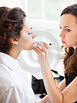 Make-up artist doing make up for young beautiful bride