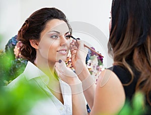 Make-up artist doing make up for young beautiful bride