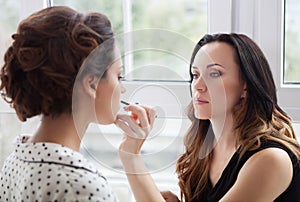 Make-up artist doing make up for young beautiful bride