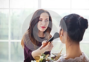 Make-up artist doing make up for young beautiful bride