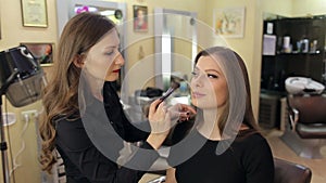 Make-up artist doing make-up for a young girl.