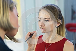 Make-up artist doing makeup to beautiful young girl