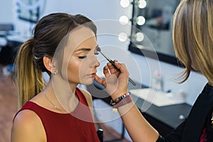 Make-up artist doing makeup to beautiful young girl