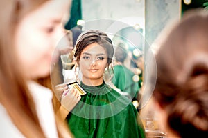 Make-up artist doing makeup for young beautiful bride applying wedding makeup in a beauty salon.