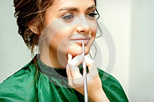 Make-up artist doing makeup for young beautiful bride applying wedding makeup in a beauty salon.