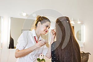 Make-up artist doing makeup for young woman