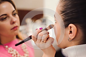 Make up artist doing professional make up of young woman. Beauty shcool.
