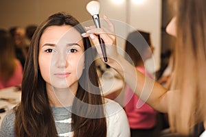 Make up artist doing professional make up of young woman. Beauty shcool.