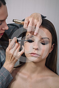 Make-up artist doing visage for beautiful teenage girl, using mascara for eyes. Make up, cosmetics, beauty standards, skin care