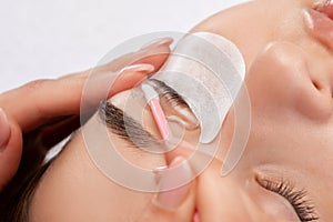 Make-up artist makes the procedure of lamination and dyeing of eyelashes to a beautiful woman in a beauty salon. Eyelash