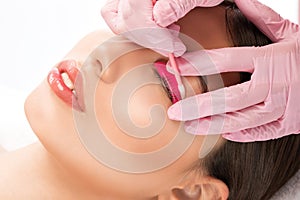 Make-up artist makes the procedure of lamination and dyeing of eyelashes to a beautiful woman in a beauty salon. Eyelash