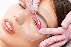 Make-up artist makes the procedure of lamination and dyeing of eyelashes to a beautiful woman in a beauty salon. Eyelash