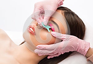 Make-up artist makes the procedure of lamination and dyeing of eyelashes to a beautiful woman in a beauty salon. Eyelash