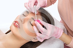 Make-up artist makes the procedure of lamination and dyeing of eyelashes to a beautiful woman in a beauty salon. Eyelash