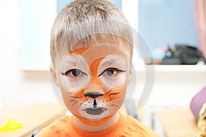 Make up artist making tiger mask for child.Children face painting. Boy painted as tiger or ferocious lion