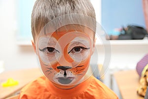 Make up artist making tiger mask for child.Children face painting. Boy painted as tiger or ferocious lion