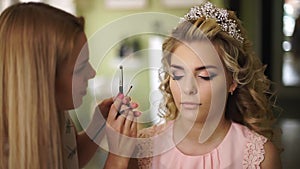 Make-up artist paints the face of the bride, in a beautiful salon. Professional makeup for woman with healthy young face