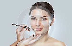 The make-up artist paints the lips of a beautiful woman,  completes the make-up in the beauty salon. Professional skin care