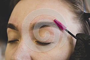 Make-up artist plucks eyebrows with tweezers to a woman. Beautiful thick eyebrows close up. beautiful female eyebrows