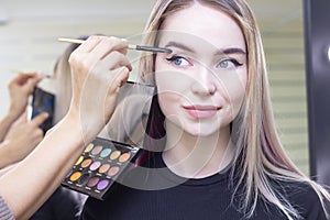 Make-up artist puts makeup on the girls eyes. eye shadow, palette. Beauty saloon.