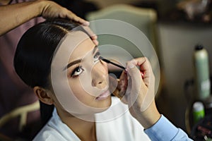 Make up artist putting on mascara on beautiful asian model