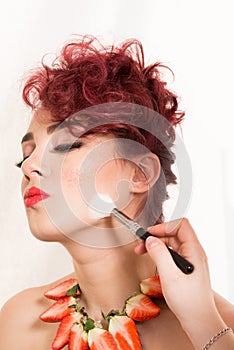 Make-up artist retouching female model`s cheek with powder brush