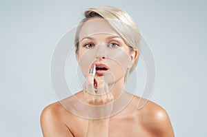 Make up. Beautiful woman applying lipstick looking at mirror