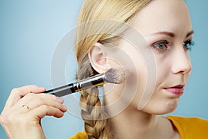 Makeup artist applying with brush rouge on female check