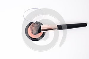 A powder make-up brush with peach colored powder in a round box photo