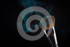 Make up brush with blue powder splashes on black background