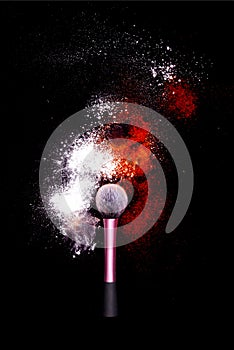Make-up brush with colorful powder on black background. Explosion stars dust with bright colors. White and green powder red