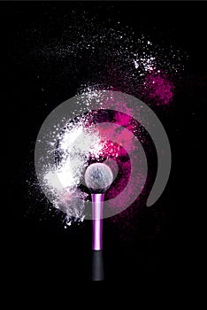 Make-up brush with colorful powder on black background. Explosion stars dust with bright colors. White and pink powder red