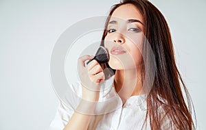 Make up brush kabuki in hand of smiling asian young woman with dark long hair on white background