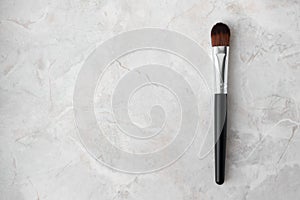 Make up brush with synthetic bristles and black wood handle on luxury marble background. Cosmetic brush for face tone, blush,