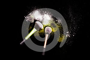 Make-up brush with white powder spilled glitter dust on black background. Makeup brush on new year`s Party with bright colors.