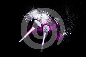 Make-up brush with white powder spilled glitter dust on black background. Makeup brush on new year`s Party with bright colors.