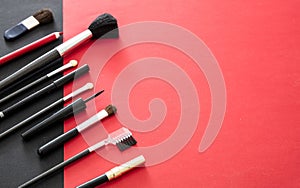 Make-up brushes set against red and black background, copy space