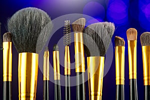 Make-up Brushes set over black holiday blinking background. Various Professional makeup brush on dark backdrop in studio