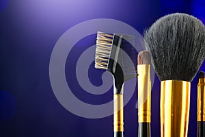 Make-up Brushes set over black holiday blinking background. Various Professional makeup brush on dark backdrop in studio