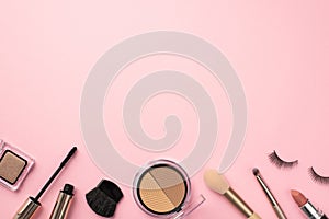 Make-up concept. Top view photo of contouring palette lipstick false eyelashes makeup brushes mascara and eyeshadow on pastel pink