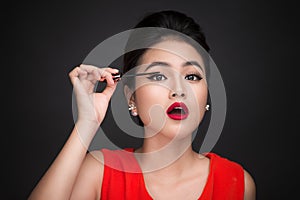 Make-up and cosmetics concept. Asian woman doing her makeup eyelashes black mascara.